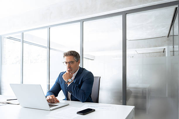 istock Focused latin senior in suit financial expert analyst thinking working on sale solution. Professional indian manager investor using pc laptop computer sitting at desk workplace in office. Copy space 2212567026