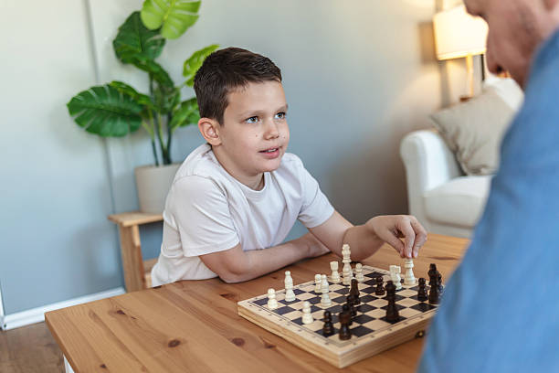 istock Father, son and chess in home with challenge, game or play with strategy for competition. Adorable boy, men and together by board for queen, king and pawn for contest, bonding and retirement. 2212567162