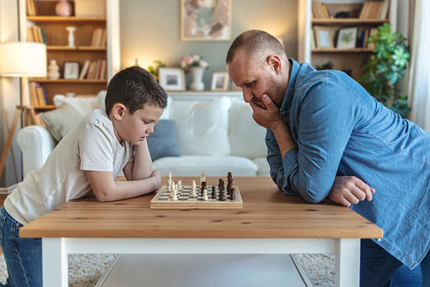 istock Father and son, chess and thinking in home, challenge with strategy, moving and ideas. Young man, boy and board game with king, queen or knight for contest, relax or conflict. 2212567267