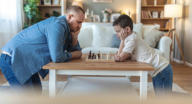 istock Father and son, chess and thinking in home, challenge with strategy, moving and ideas. Young man, boy and board game with king, queen or knight for contest, relax or conflict. 2212567293