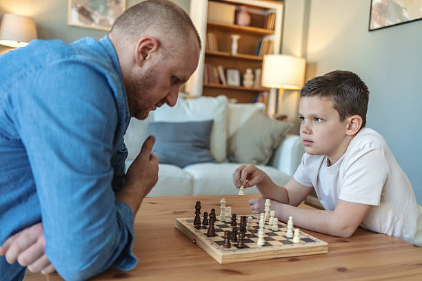istock Father and son, chess and thinking in home, challenge with strategy, moving and ideas. Young man, boy and board game with king, queen or knight for contest, relax or conflict. 2212567472