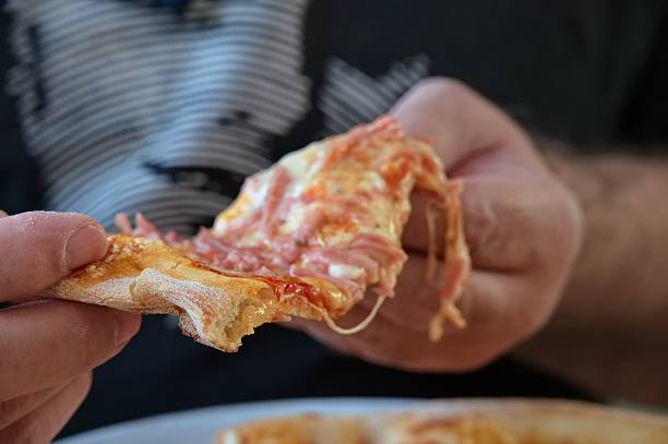 istock Midsection of man holding pizza 2212567604