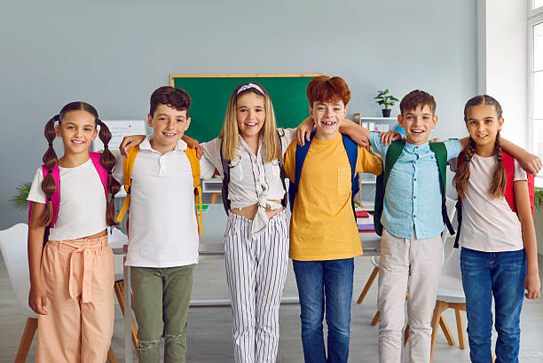 istock Group of elementary school students standing together in row and hugging 2212568954
