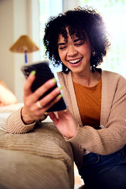 istock Cheerful young woman using smartphone and smiling 2212569215