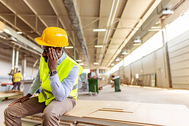 istock Concerned Construction Worker Sitting in Factory Workspace with Safety Gear 2212569544