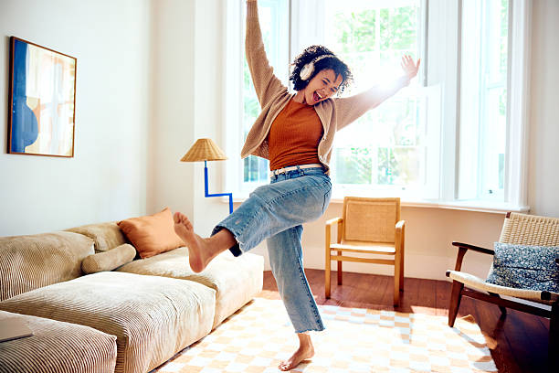 Ecstatic young woman wearing headphones, listening to music and dancing barefoot stock photo
