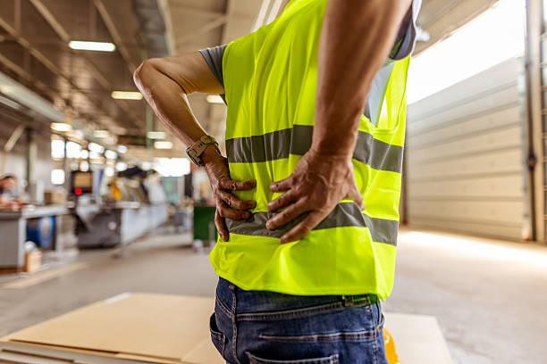 istock Worker in High-Visibility Vest Experiencing Back Pain in Industrial Setting 2212570507