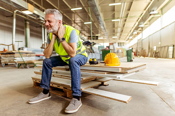 Worker Resting Inside Spacious Workshop with Safety Helmet and Materials Nearby stock photo