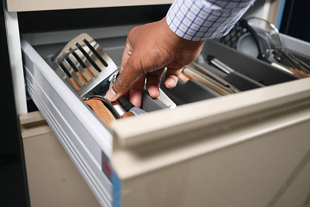istock Hand Organizing Kitchen Drawer with Utensils for Efficiency 2212571769