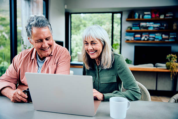 istock Cheerful senior couple using laptop at home, smiling 2212575683