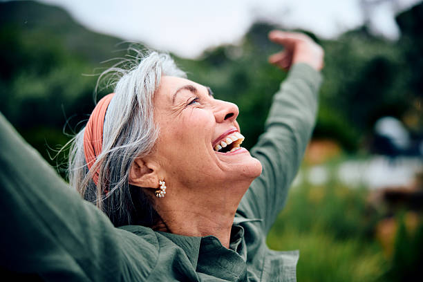 Portrait of carefree senior woman with arms out, looking up, smiling stock photo
