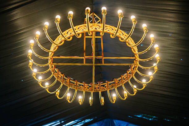 istock Ornate golden chandelier with glowing bulbs and dark fabric backdrop 2212578301