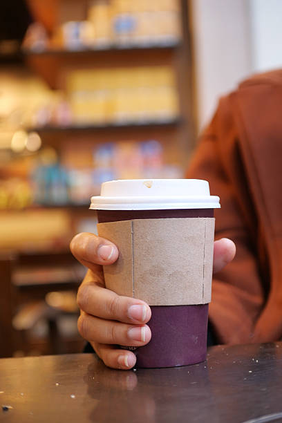 istock holding a take away kraft coffee cup with happy new year wish on it 2212579105