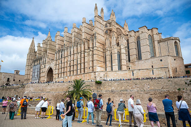 18 April 2025 Palma de Mallorca, Spain. Crowds gather outside the majestic La Seu Cathedral in Palma, Mallorca, during Good Friday celebrations under a bright, partly cloudy sky.