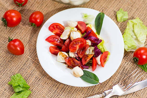 Classic Italian caprese salad for dinner, on a dark rustic table.