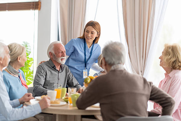 istock Nurturing Caregiver Engaging with Seniors at Breakfast 2212586876