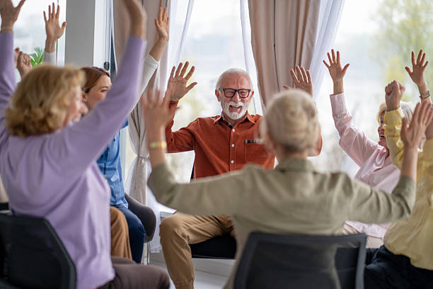 istock Group Therapy Session with Seniors Raising Their Hands Together 2212586916
