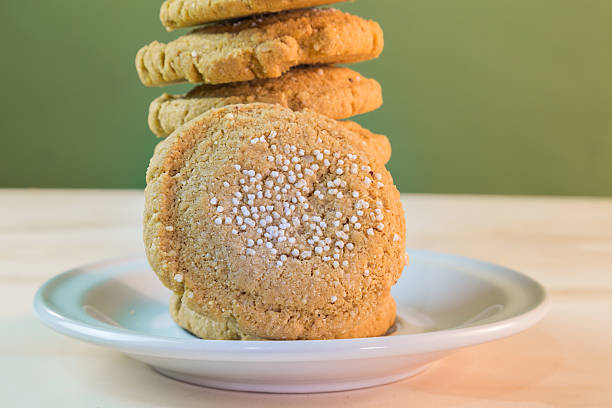 A group of peanut butter cookies on a white plate with a bite out of one and photographed from overhead.