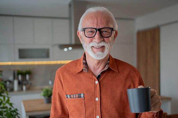 istock Senior man smiling and holding a mug in his modern kitchen 2212589462