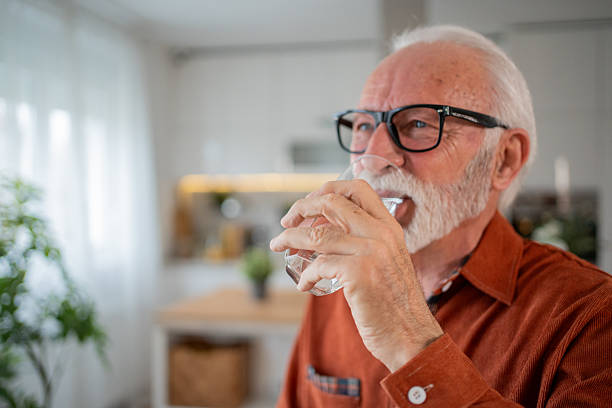 istock Senior man drinking water in his kitchen 2212589584