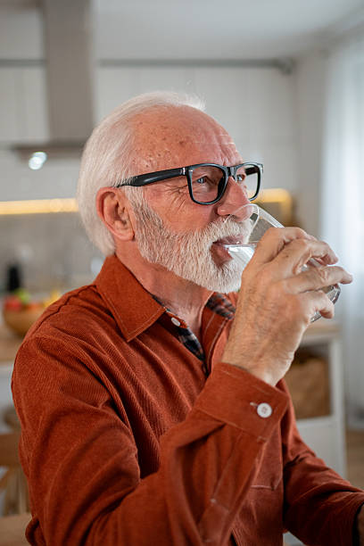 istock Senior man drinking water in the kitchen 2212589592