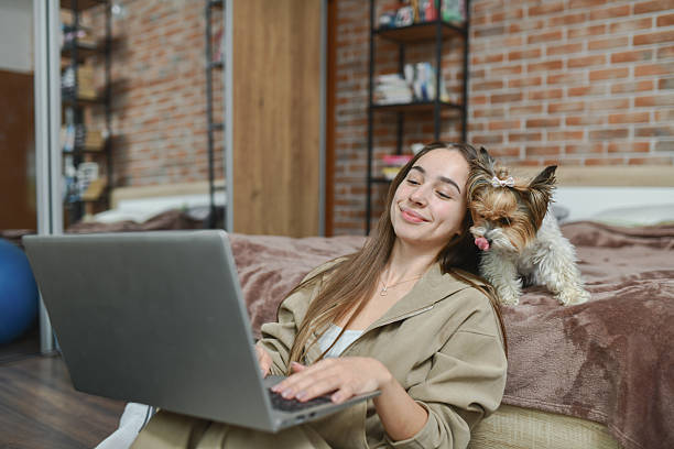 istock Smiling Female Having Fun While Studying As Her Cute Dog is Keeping Her Company 2212589601