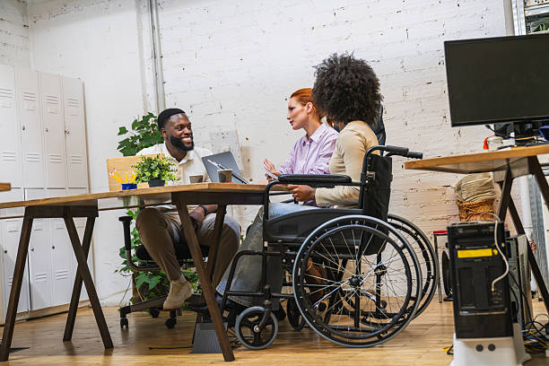 istock Multiethnic team collaborating in a modern coworking space with two people using wheelchairs 2212590957