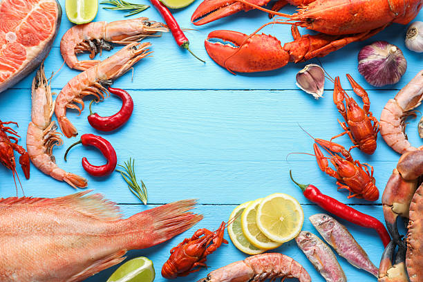 istock Frame of different sea food on light blue wooden table, flat lay. Space for text 2212590996