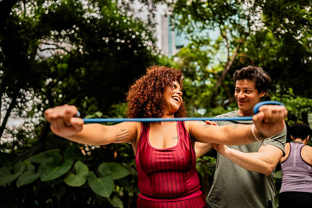 istock Instructor man helping woman using rubber band outdoors 2212594489
