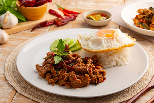 istock Stir fried sliced Beef with dry chilli and Holy Basil and cooked thai rice topped with fried egg in white plate. 2212595739