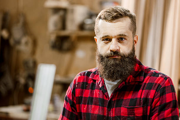 istock Skilled craftsman with beard standing in workshop surrounded by tools and wood materials 2212597598