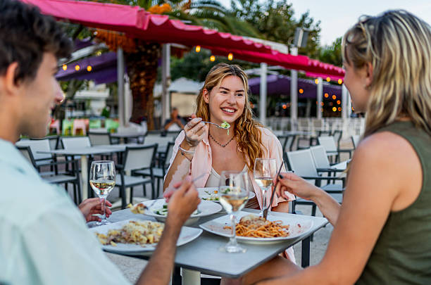 istock Three young adults enjoying dinner at an outdoor restaurant 2212598015
