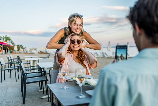 istock Friends taking pictures at beach restaurant while having dinner 2212598591