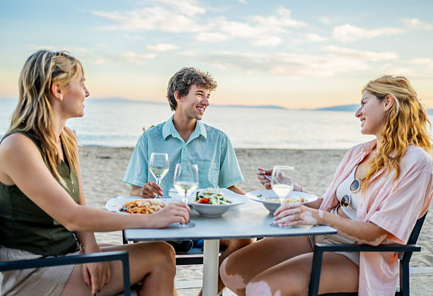 istock Friends enjoying a beachfront dinner at sunset 2212598813