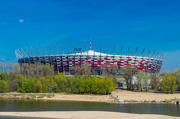 The National Stadium in Warsaw, also known as PGE Narodowy, is a modern, multi-purpose stadium located on the Vistula River's right bank. It hosts major sports events, concerts, and cultural activities. The stadium's distinctive red and white facade represents the Polish national colors, making it a prominent landmark. The panoramic view of the stadium showcases its impressive architecture and its role as a hub for national events.