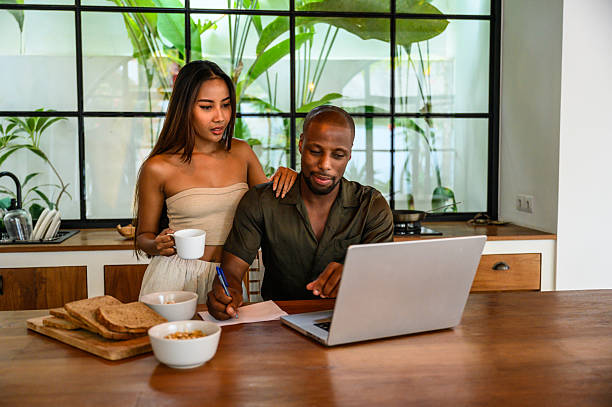 Couple working together on a laptop during breakfast in a bright kitchen