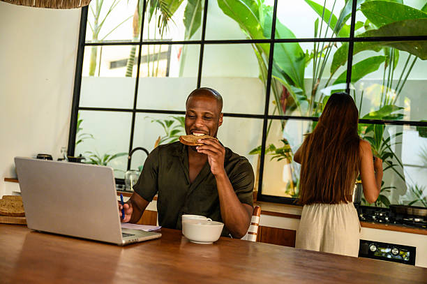 istock Man enjoying meal while working on a laptop in a modern kitchen setting 2212601764