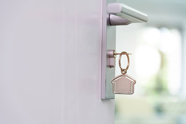 Key with metallic keychain on pale pink background, space for text