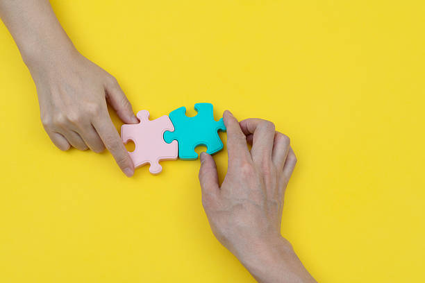 istock Two people put jigsaw puzzle pieces together 2212602887