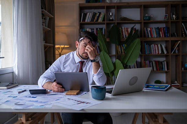 istock Serious businessman thinking of problem solution working late in office.Stressed business man analyzing trading stock market trading fall down. 2212603573