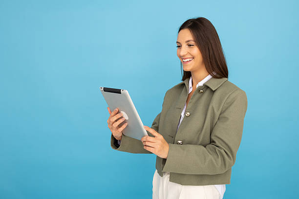 istock Young businesswoman smiling while using digital tablet on blue background 2212604456
