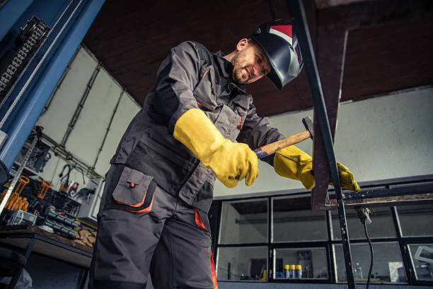 Metal worker hammering metal frame