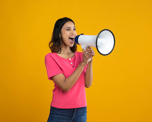 istock Woman shouting over megaphone on yellow background 2212607210