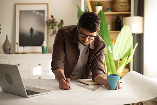 istock Above view of young building contractor analyzing plans while working at home office. 2212607282