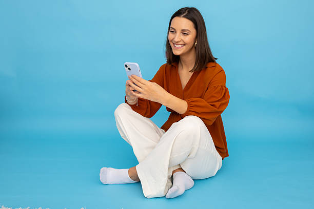 istock Woman checking smartphone while relaxing cross-legged on floor 2212607463