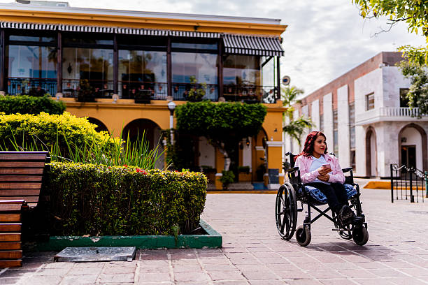 istock Young wheelchair woman using mobile phone at town square 2212607636