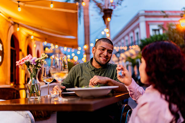 istock Young wheelchair couple talking during dinner at restaurant 2212609515