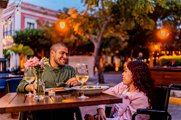 istock Young wheelchair couple talking during dinner at restaurant 2212609574