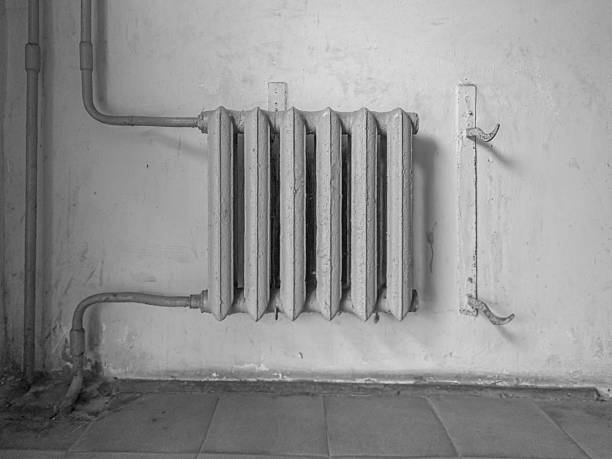 istock Vintage cast iron radiator attached to an old wall with exposed pipes. 2212610186