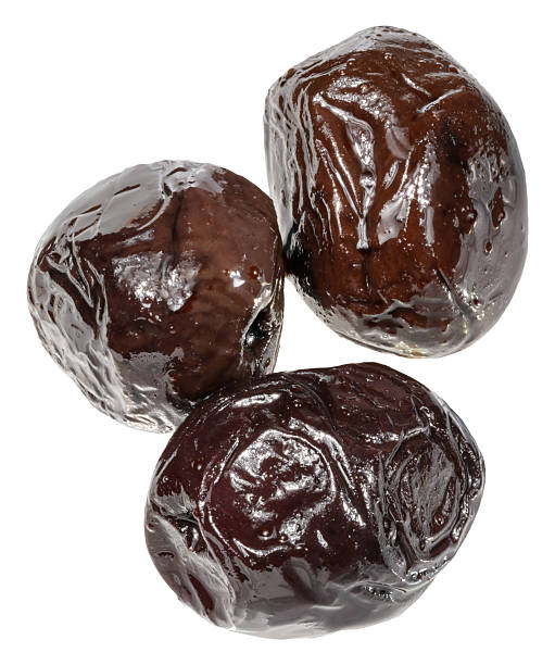 istock Three smooth, pitted black olives with a shiny, slightly wet surface are grouped together, isolated background 2212615726